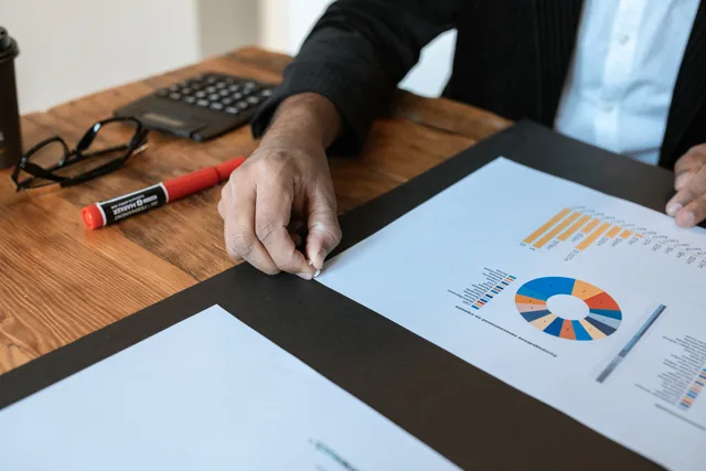 Close-up of a business setting with charts, documents, and a hand pointing. Reading a productivity software agency record, with HSO as a worked dossier