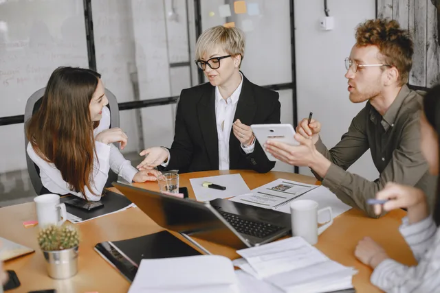Group of business professionals engaged in a meeting discussing strategies and cooperation. Where AI fits in productivity software, and the gate to pass before it acts
