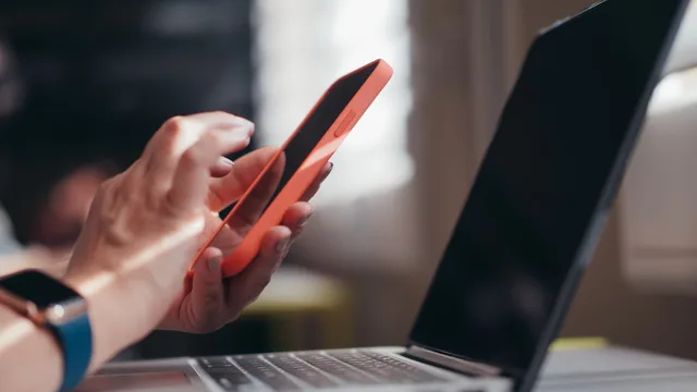Adult using a smartphone and laptop indoors, showcasing modern technology and multitasking. Four ways to tell whether productivity software actually changed anything