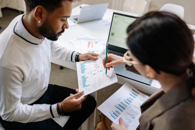 Two professionals reviewing data and graphs in a modern office setting for analysis. A productivity benchmark is a reference class, not a target