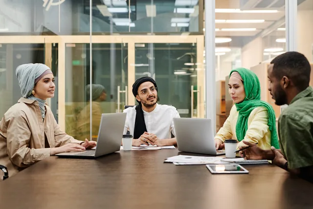 A diverse group discussing ideas in a modern office setting, using laptops and tablets. Six signs of real demand for a productivity software idea, and how to read them