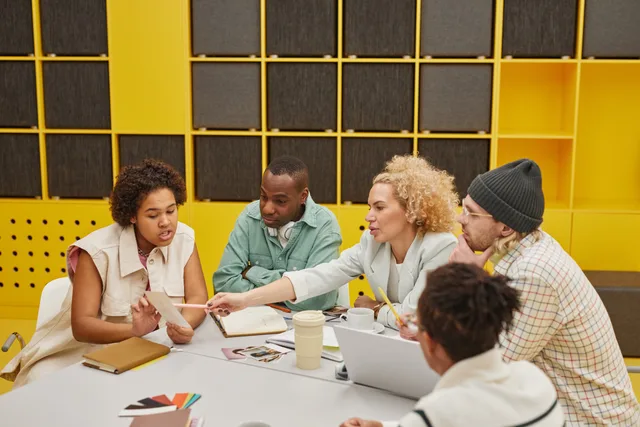 A group of coworkers engaged in a collaborative meeting at a modern office table. Assessing England's productivity software market by the job, not the category